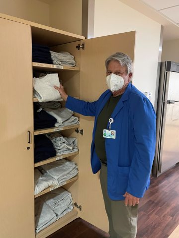 Man wearing a face mask restocks linen shelves in hospital